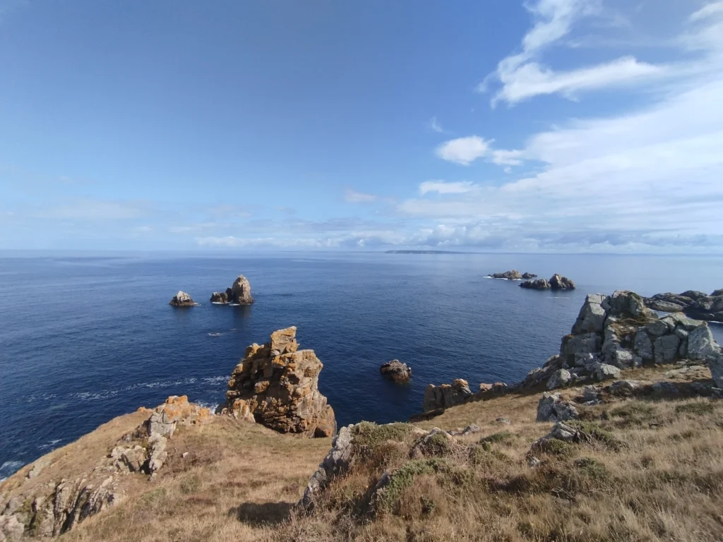 photo du cap sizun prise depuis le sentier côtier. On y voit la mer d'iroise, les îlots et la presqu'île de crozon au loin.